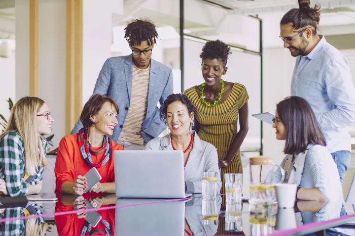Multigeneration and diverse business team working together in front of shared computer, representing learning about AI together.