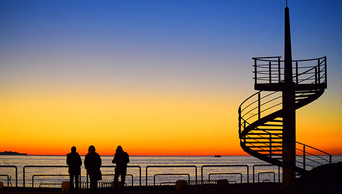 Three people watching a sunset