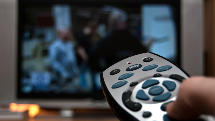 Someone pointing a remote at a TV screen.