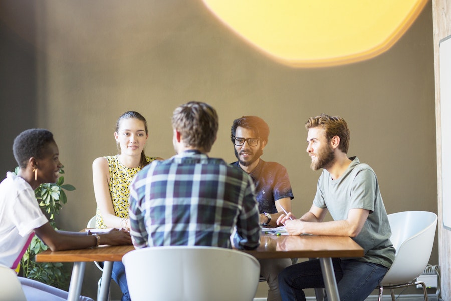 A group of people are talking around a table indicating social sensitivity.